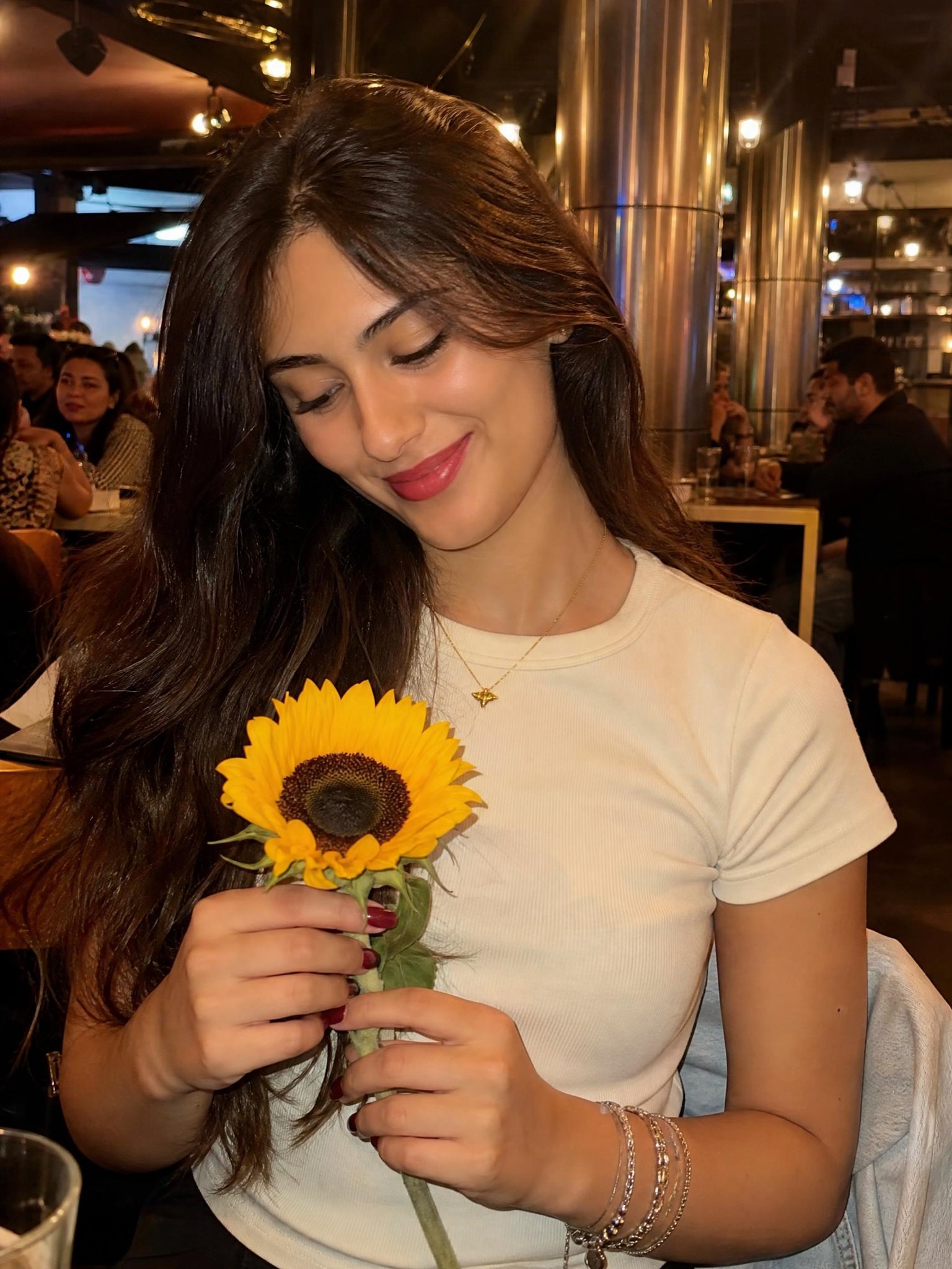 手持向日葵的棕发年轻女性室内餐厅暖色调中景 / Young Woman Holding Sunflower In Warm Lit Restaurant,海报与插画,海报、插画、海报与插画,案例输出图 1